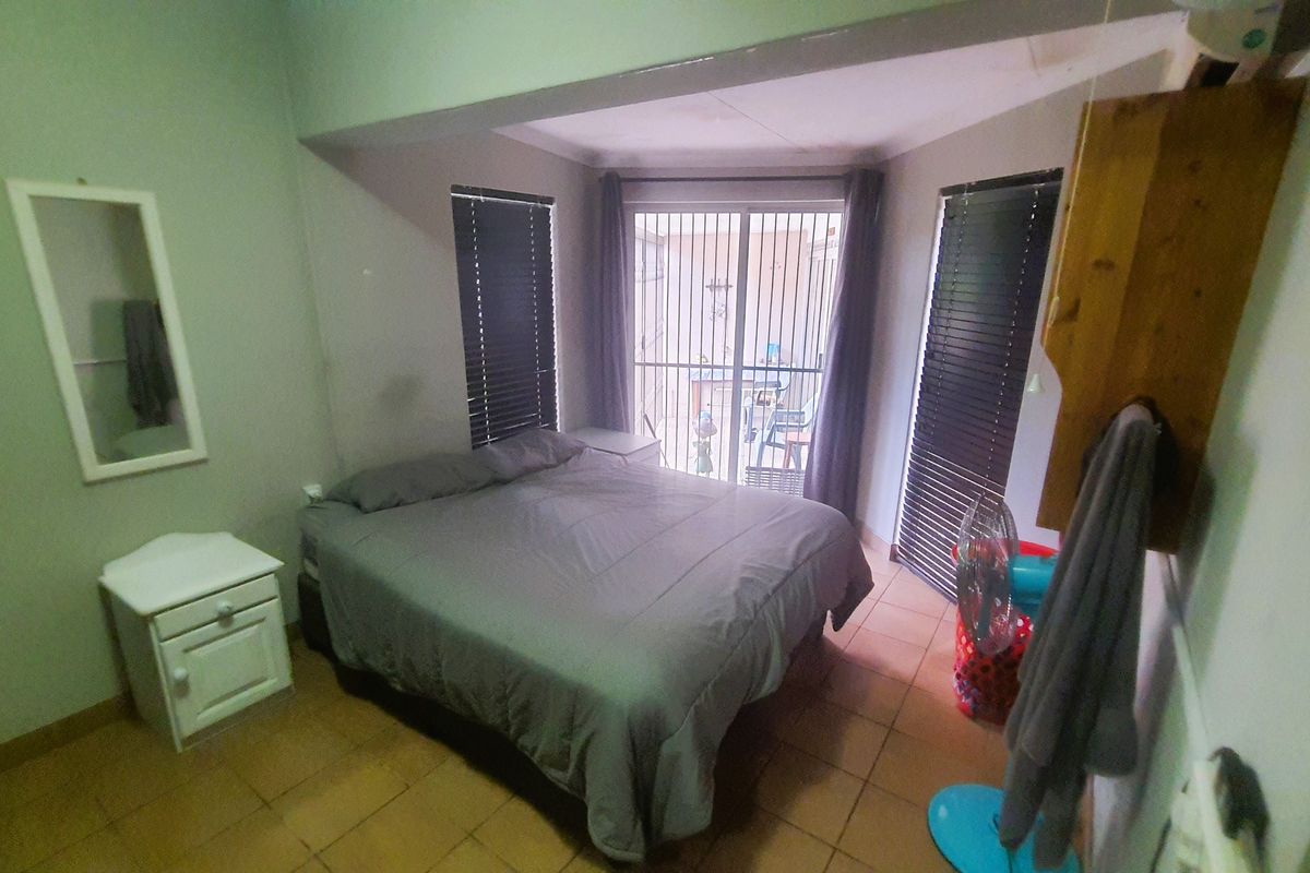 A bedroom featuring tiled flooring, built-in window blinds, and a sliding door providing access to an outdoor area.