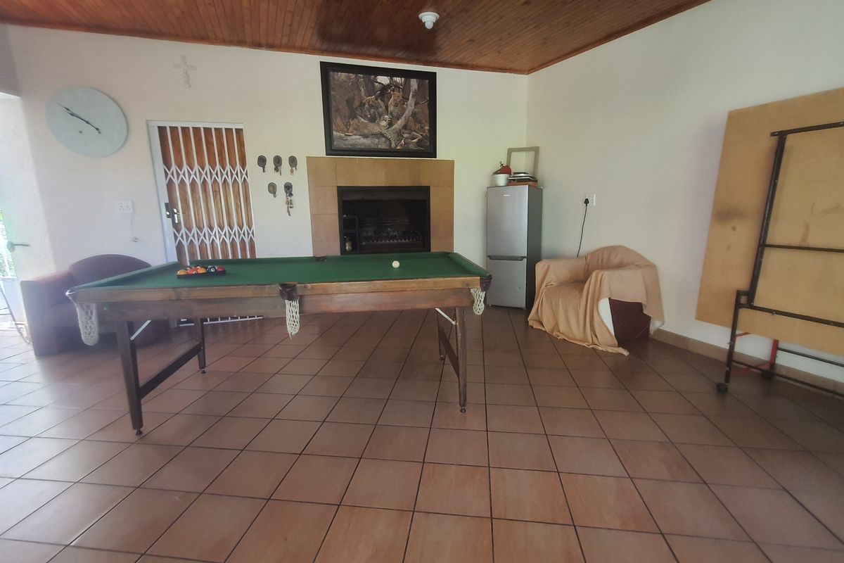 A spacious living area featuring tiled flooring, a built-in fireplace, and a timber-paneled ceiling, providing a versatile space for relaxation or entertainment.