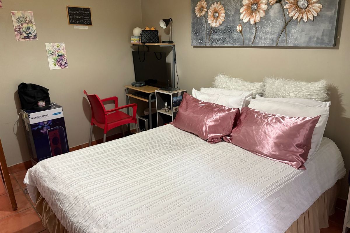 A functional bedroom featuring tiled flooring and neutral wall tones, providing a comfortable and practical living space.