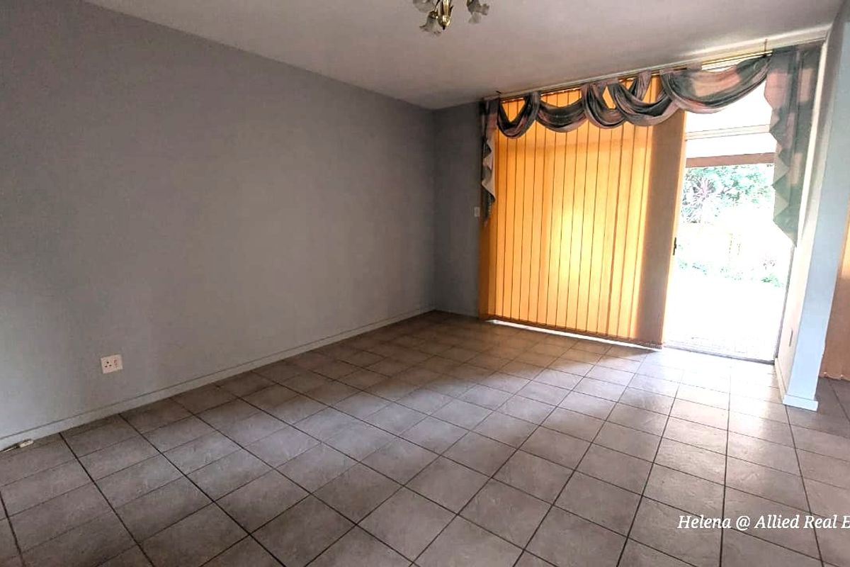 A spacious living area featuring neutral tiled flooring and large sliding glass doors that provide direct access to the outdoor space.