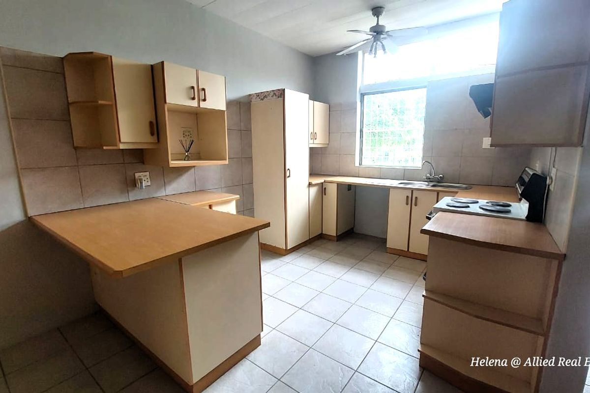 A functional kitchen featuring tiled flooring, built-in cabinetry, a double sink, and a stove, offering a practical layout for daily meal preparation.