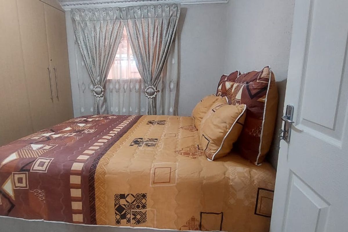 A bedroom featuring built-in floor-to-ceiling wardrobes and a window with curtain treatments.