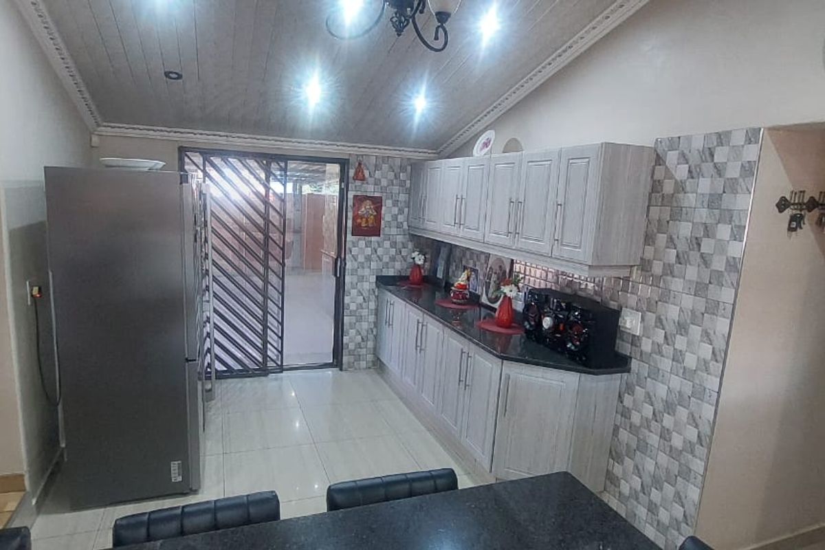 A functional kitchen featuring light-toned cabinetry, dark granite countertops, tiled backsplash, and a sliding door providing access to the outdoor area.