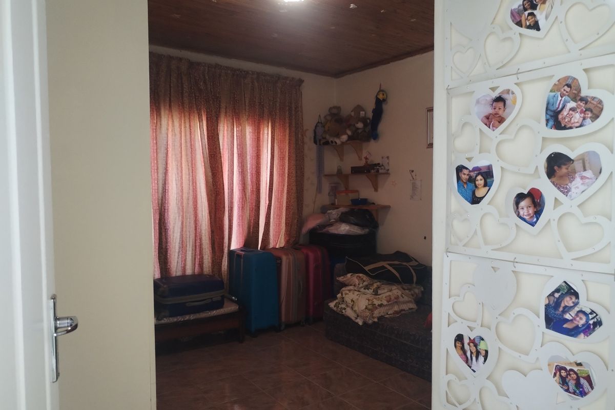 A bedroom featuring tiled flooring and a timber-paneled ceiling, viewed through a decorative room divider.