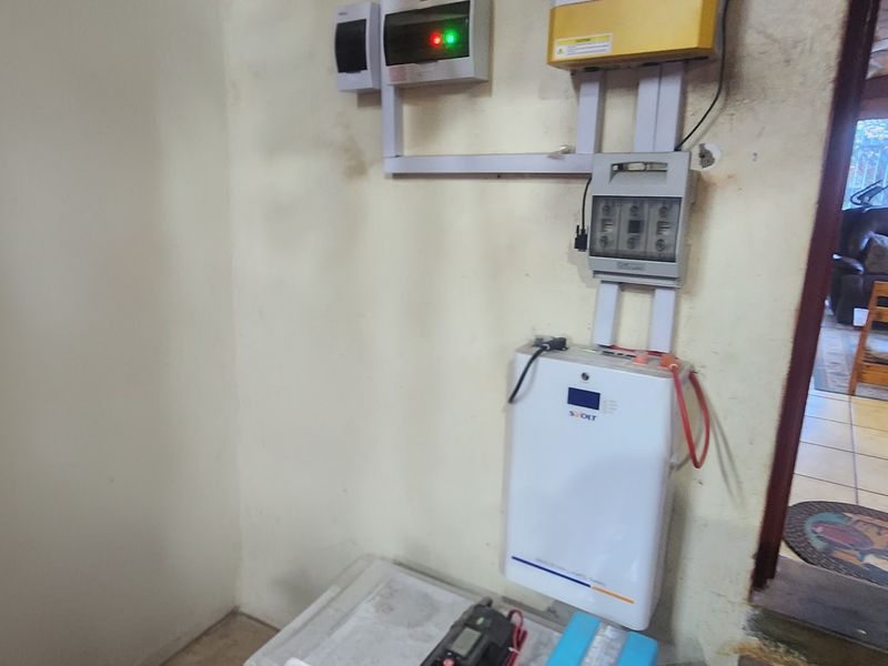 Utility area featuring a wall-mounted solar inverter and electrical distribution board setup.