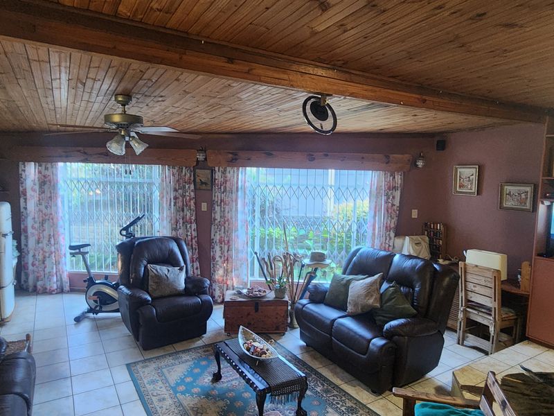 Spacious living room featuring a timber-clad ceiling, tiled flooring, and built-in cabinetry, offering a traditional aesthetic with potential for modern updates.