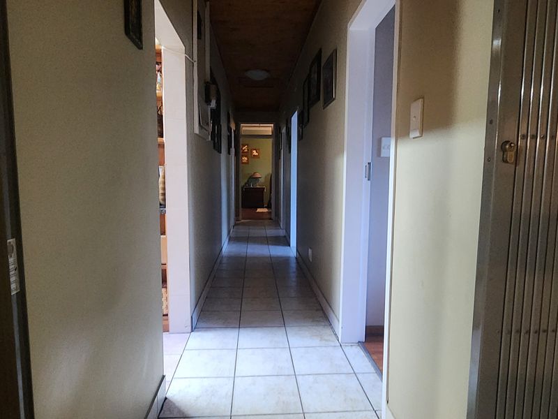 A long interior hallway featuring tiled flooring and a timber-paneled ceiling, providing access to multiple rooms within the home.