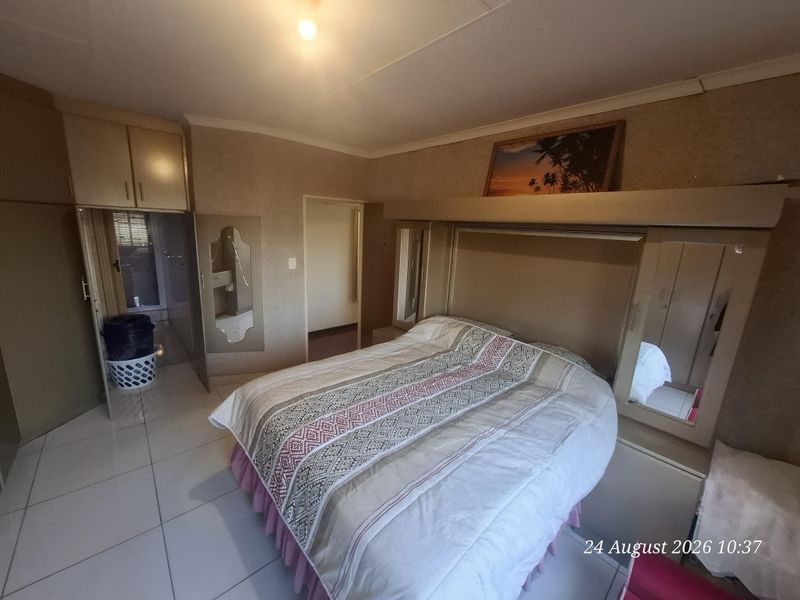 A bedroom featuring built-in cupboards, tiled flooring, and direct access to an en-suite bathroom.