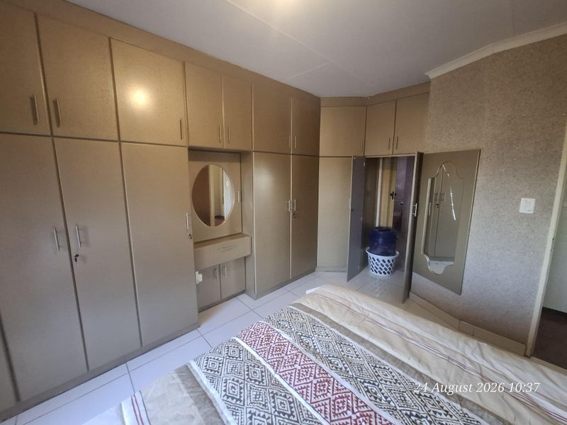 Bedroom featuring extensive built-in cabinetry with an integrated vanity unit and tiled flooring.