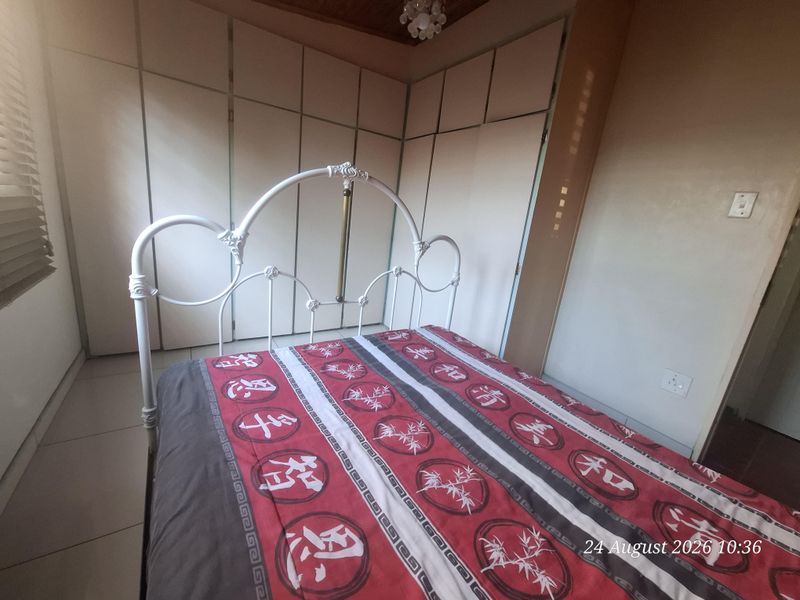 A bedroom featuring built-in cupboards and tiled flooring, providing functional storage space.