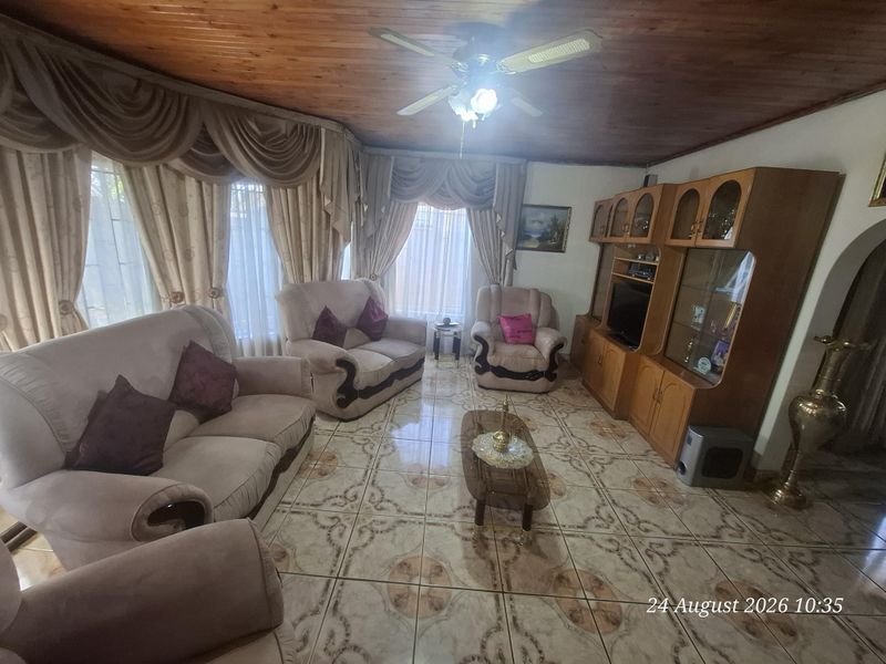 A living room featuring a timber ceiling, ceiling fan, and patterned ceramic floor tiles.