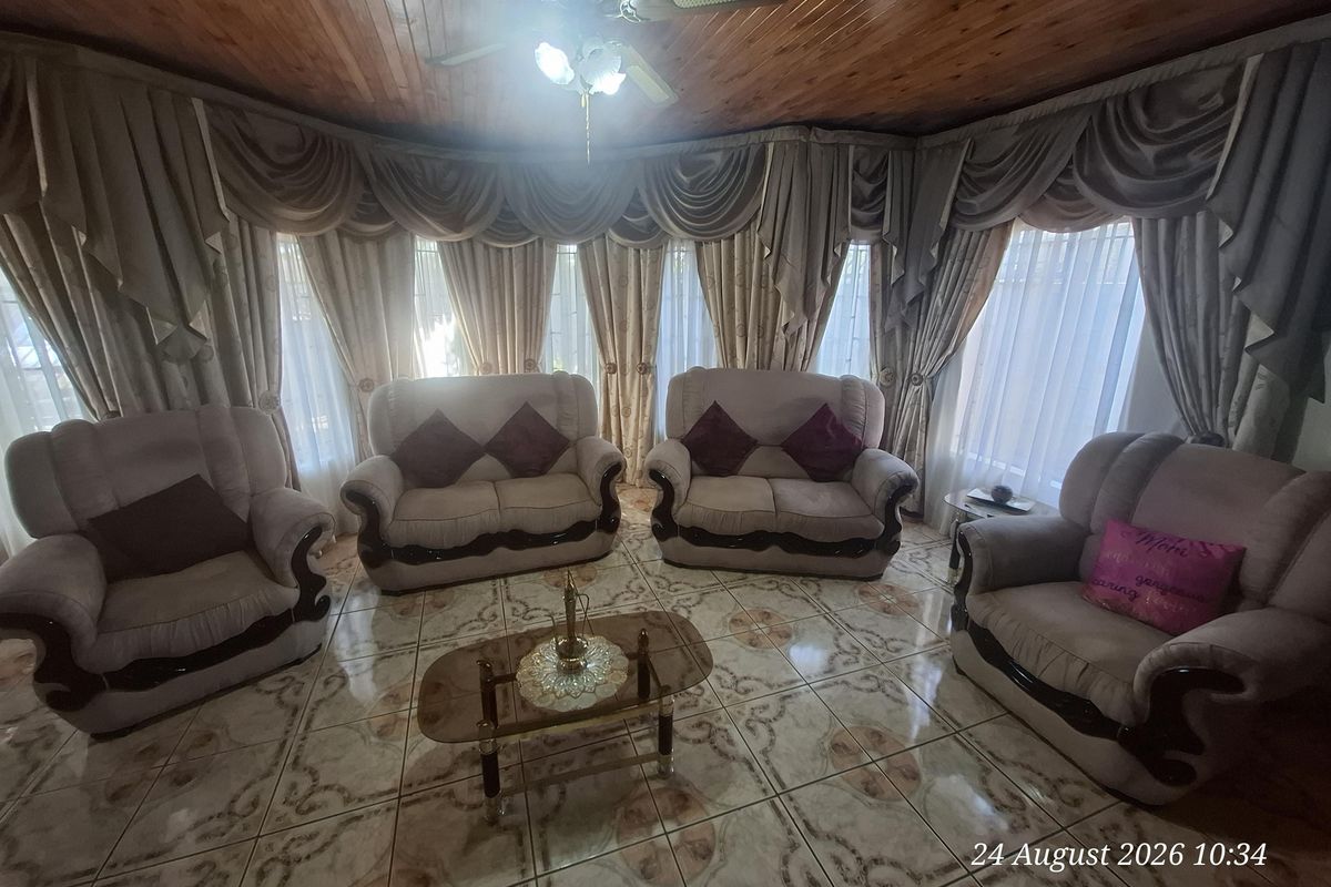 A living room featuring a timber tongue and groove ceiling, ceiling fan, and patterned ceramic floor tiles.