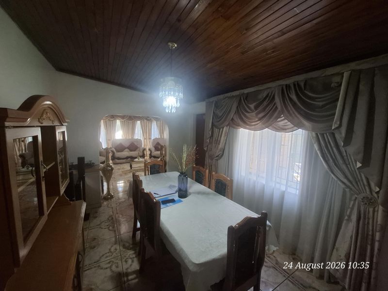 Dining room featuring a timber tongue and groove ceiling, ceramic tiled flooring, and an archway leading to the adjacent living area.