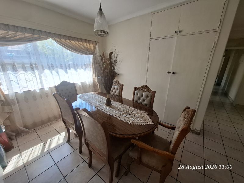 A dining room featuring tiled flooring, a built-in storage cupboard, and a pendant light fixture, offering a functional space for family meals.