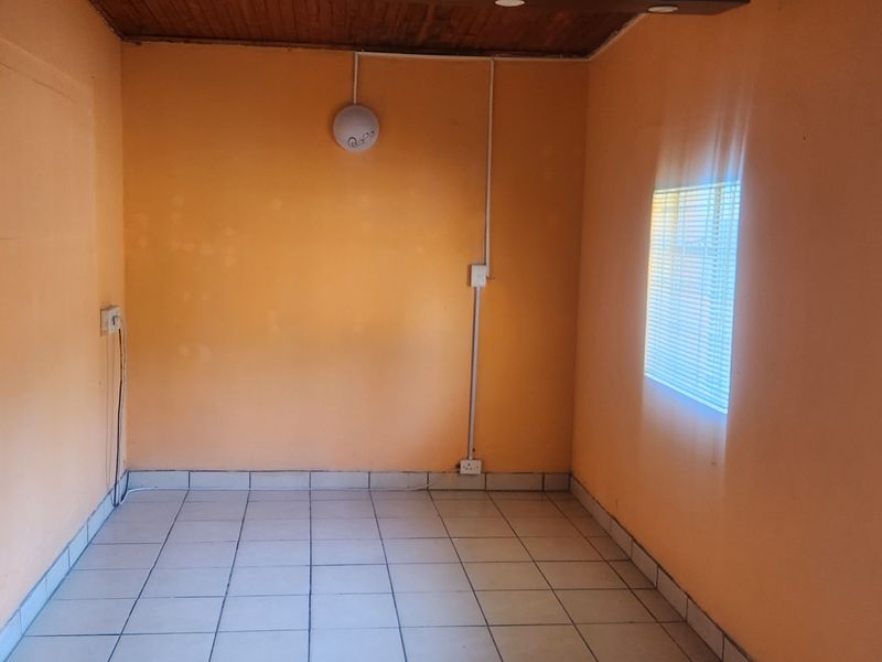 An empty room featuring tiled flooring, a timber ceiling, and surface-mounted electrical conduit, offering a blank canvas for renovation.