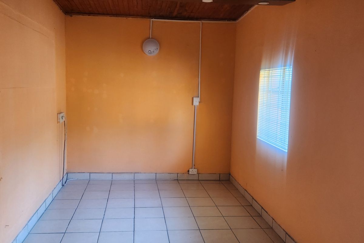 An empty room featuring tiled flooring, a timber ceiling, and surface-mounted electrical conduit, offering a blank canvas for renovation.