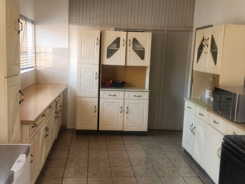 A functional kitchen featuring dated built-in cabinetry, tiled flooring, and tiled splashbacks, offering a practical layout with ample storage space.