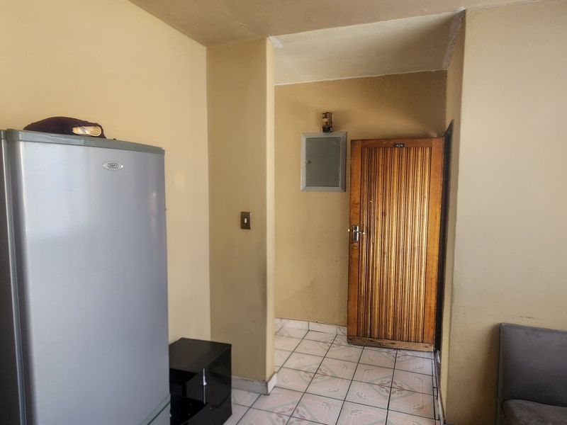 An entry area featuring tiled flooring and a wooden door, showing signs of wear and requiring cosmetic updates.