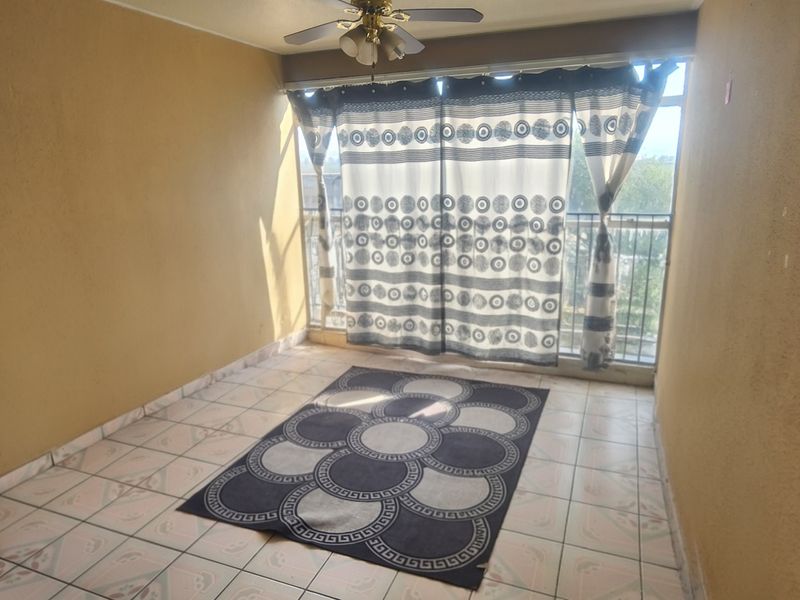 A covered balcony area featuring tiled flooring, a ceiling fan, and a metal balustrade, offering an open space ready for outdoor seating.