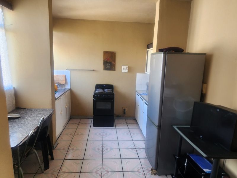 A functional kitchen area featuring tiled flooring, built-in cabinetry, and a freestanding stove, offering a practical layout for daily meal preparation.