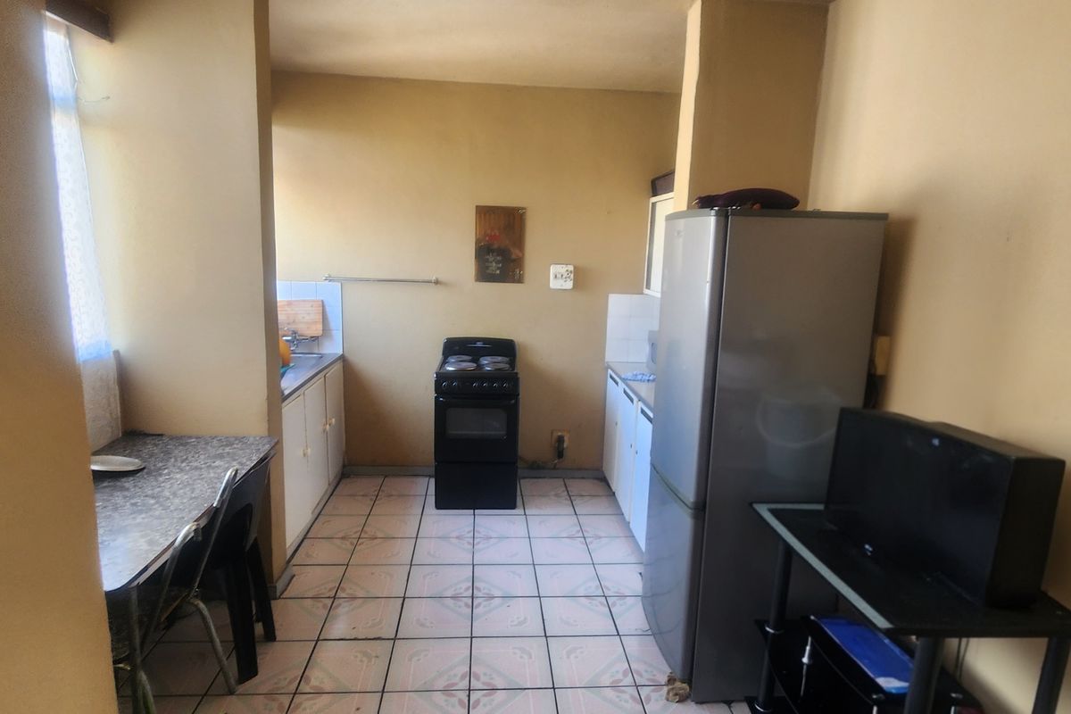 A functional kitchen area featuring tiled flooring, built-in cabinetry, and a freestanding stove, offering a practical layout for daily meal preparation.