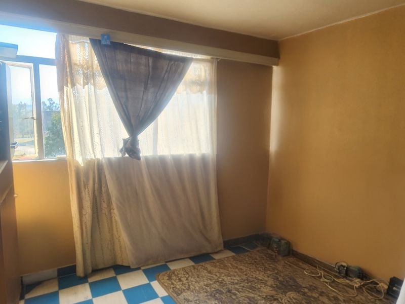 A vacant bedroom featuring tiled flooring and a window, offering a blank canvas for potential renovation and modernization.