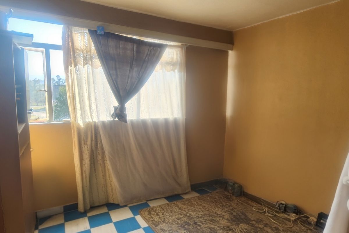 A vacant bedroom featuring tiled flooring and a window, offering a blank canvas for potential renovation and modernization.