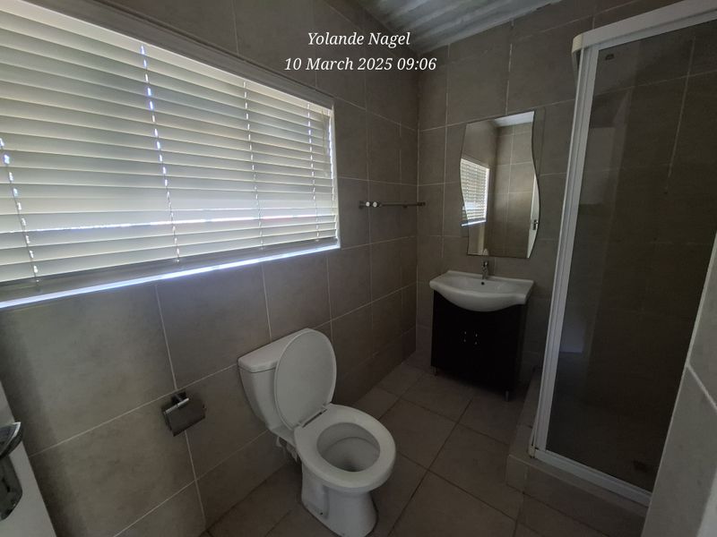 A functional bathroom featuring tiled walls and floors, a vanity with basin, a toilet, and a separate shower enclosure.