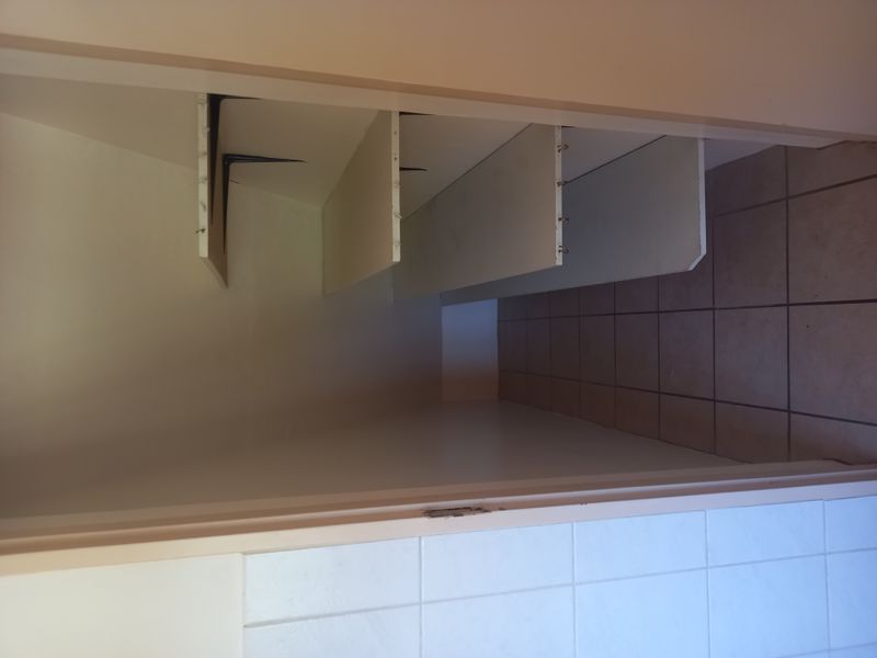 A compact walk-in storage or pantry area featuring tiled flooring and multiple built-in wall-mounted shelves.