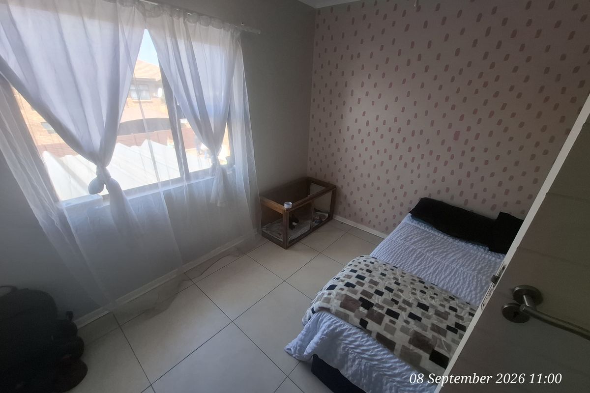 A bedroom featuring tiled flooring and a patterned accent wall, providing a functional space with natural light.