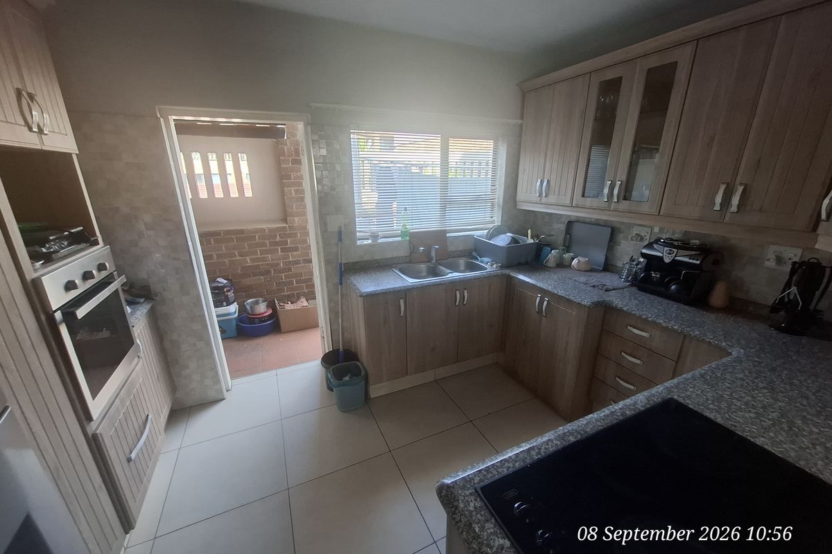 Functional kitchen featuring laminate cabinetry, granite countertops, built-in oven, and electric hob, with direct access to an outdoor area.