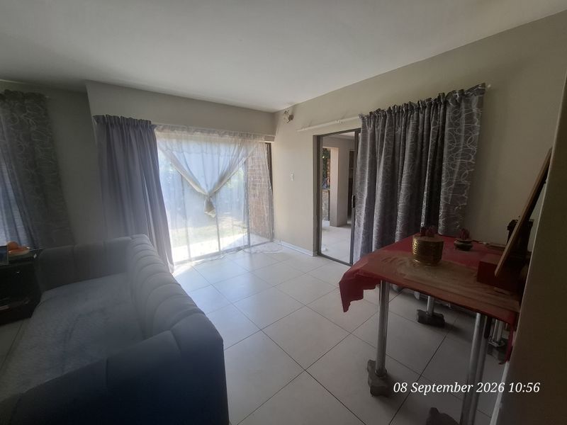 A living room featuring tiled flooring and sliding glass doors that provide access to the outdoor area.
