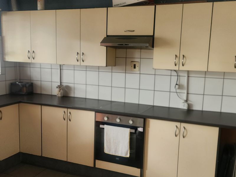 Functional kitchen featuring built-in cabinetry, laminate countertops, tiled backsplash, and integrated oven with extractor fan.