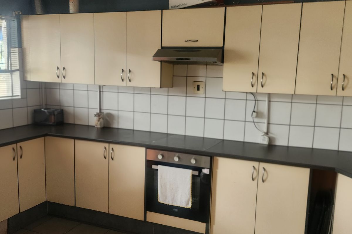 Functional kitchen featuring built-in cabinetry, laminate countertops, tiled backsplash, and integrated oven with extractor fan.