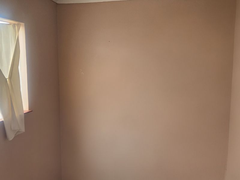 A vacant bedroom featuring a single window, requiring cosmetic updates and finishing to the wall surfaces.