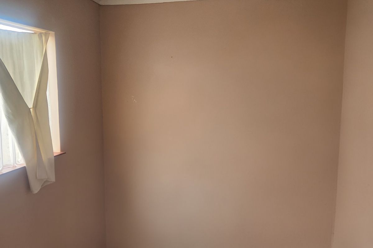 A vacant bedroom featuring a single window, requiring cosmetic updates and finishing to the wall surfaces.