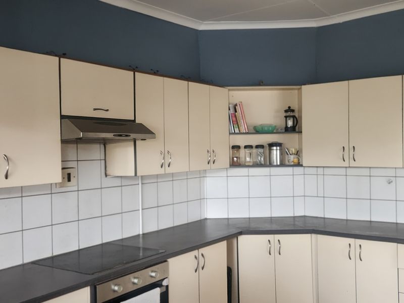 A functional kitchen featuring cream-colored cabinetry, a tiled backsplash, and integrated appliances including an oven and extractor fan.