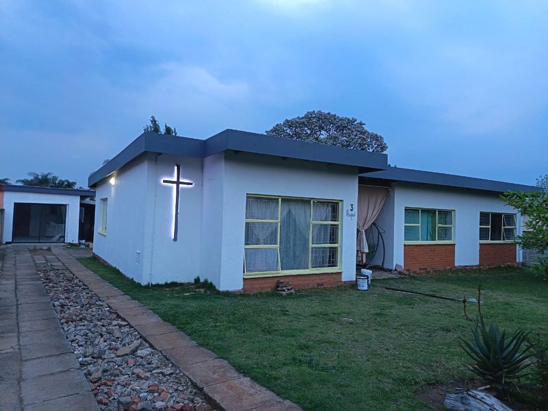 Front view of a single-story house featuring a flat roof, brick base detailing, and a paved driveway approach.