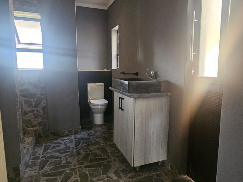 A modern bathroom featuring a vessel sink vanity, toilet, and tiled flooring with a dedicated shower area.