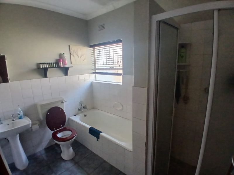 A functional bathroom featuring a pedestal basin, toilet, built-in bathtub, and a separate shower enclosure with tiled finishes.