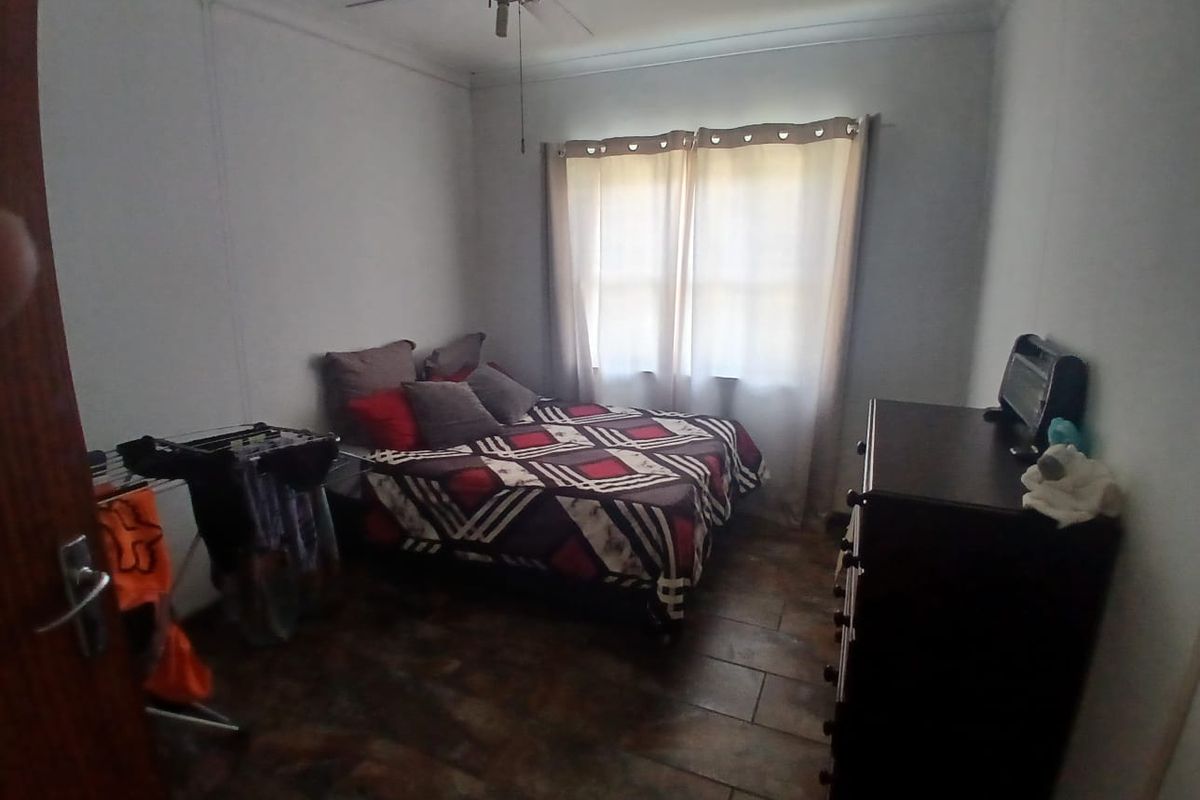A standard bedroom featuring tiled flooring and a ceiling fan, providing a functional space with natural light from the window.