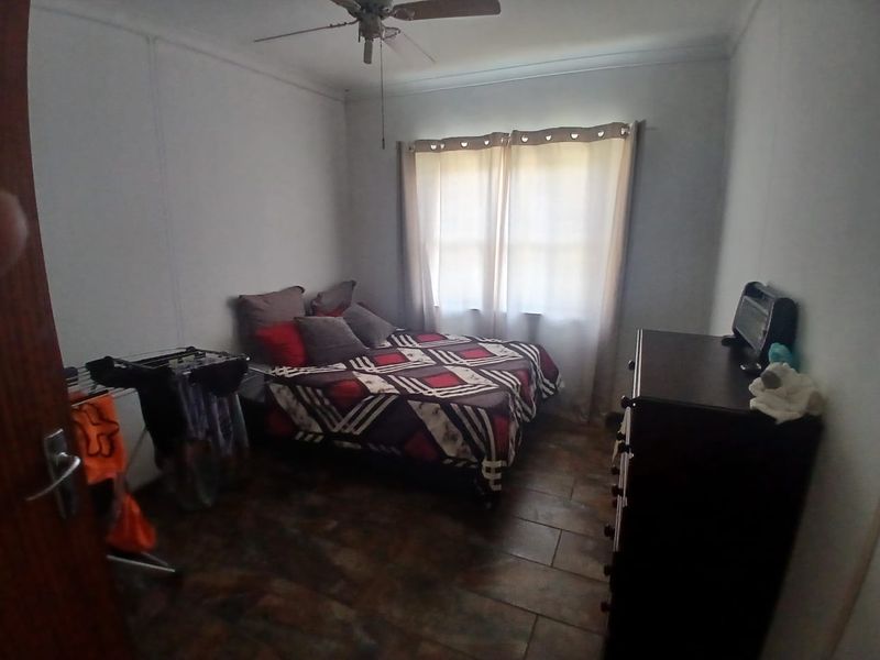 A standard bedroom featuring tiled flooring and a ceiling fan, providing a functional space with natural light from the window.