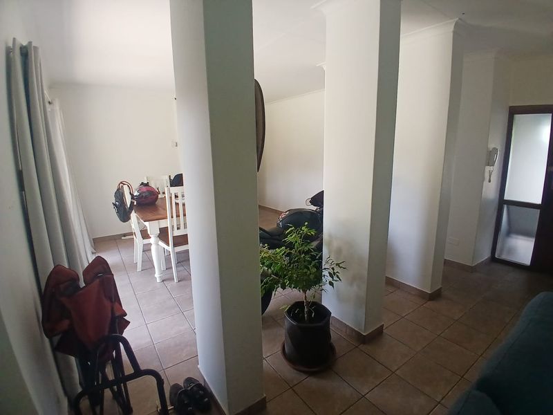 Open plan living and dining area featuring tiled flooring and structural columns, providing a versatile space for family living.
