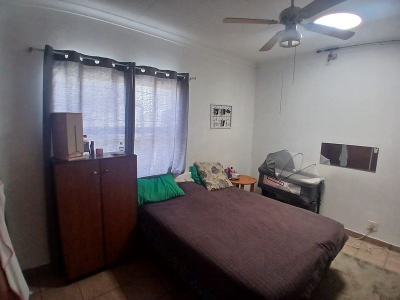 A functional bedroom featuring tiled flooring and a ceiling fan, providing a basic living space with standard finishes.