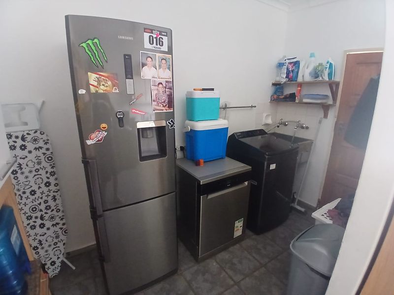 A functional laundry area featuring a utility sink, tiled flooring, and wall-mounted storage shelving.