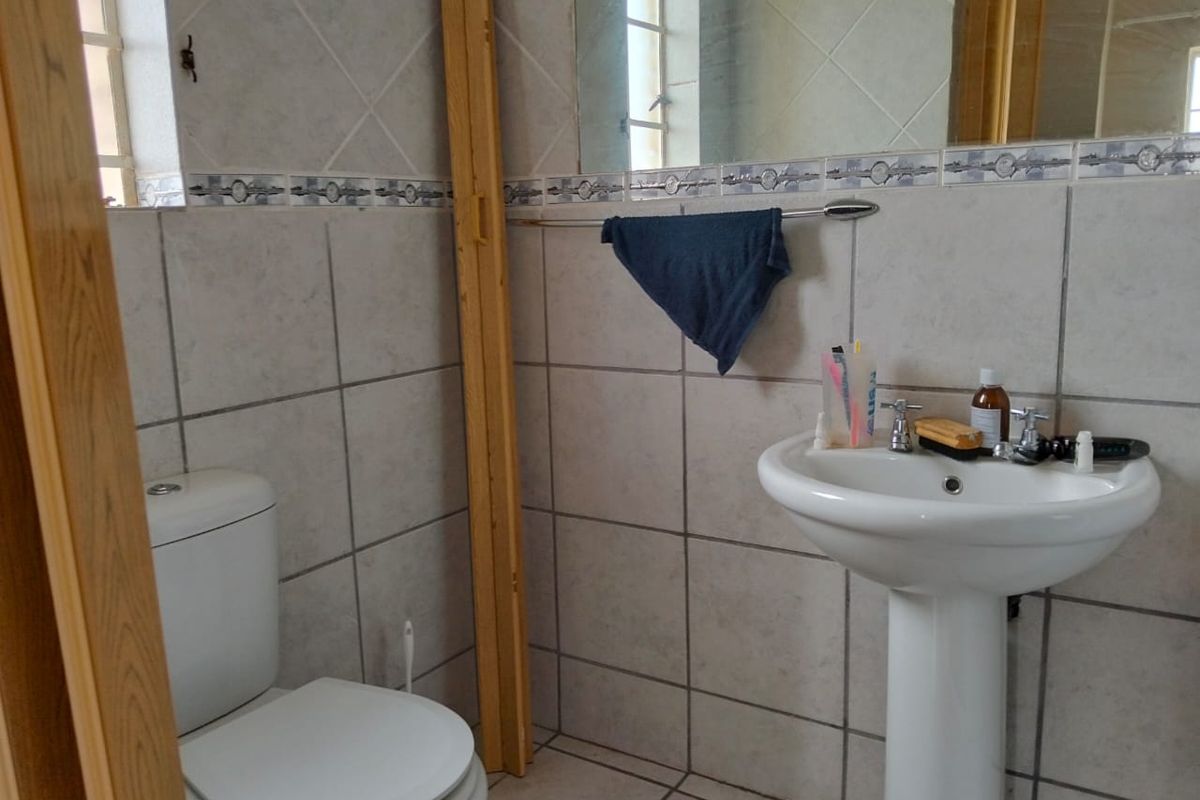 A dated bathroom featuring a pedestal basin, toilet, and tiled walls. The space requires cosmetic updates to improve its overall condition and aesthetic appeal.