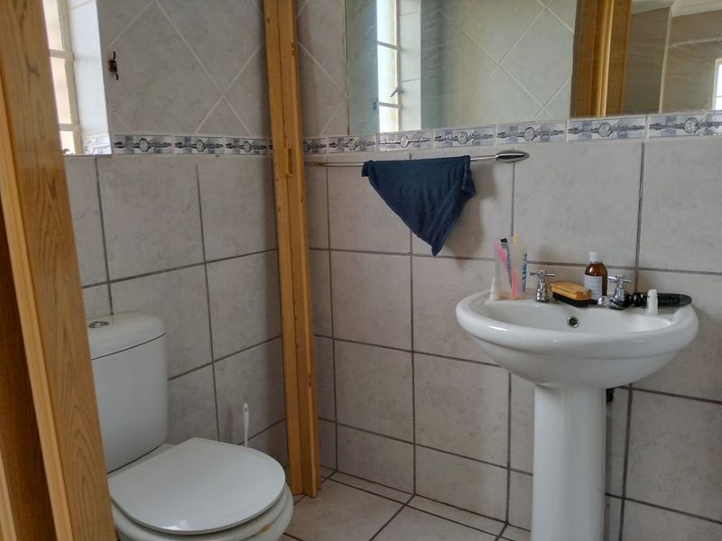 A dated bathroom featuring a pedestal basin, toilet, and tiled walls. The space requires cosmetic updates to improve its overall condition and aesthetic appeal.