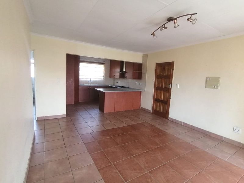 Open plan living and kitchen area featuring tiled flooring, built-in cabinetry, and a functional kitchen layout with a breakfast counter.