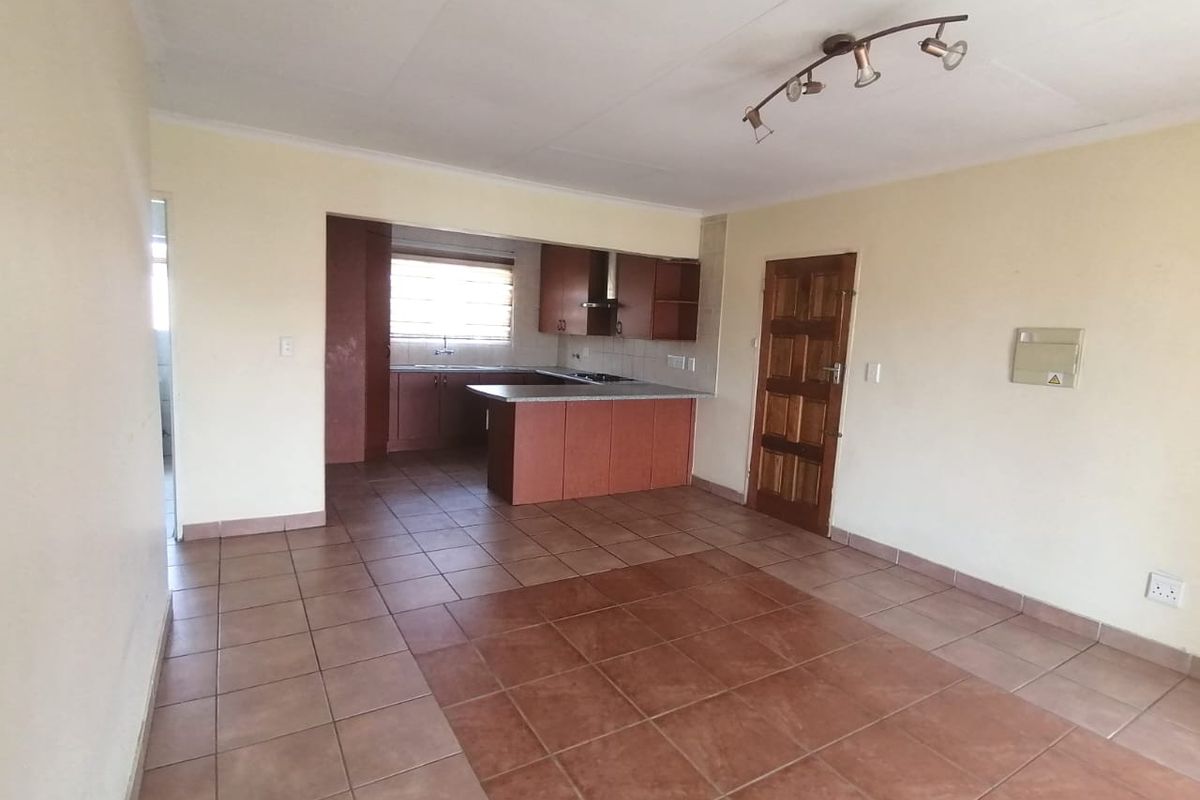 Open plan living and kitchen area featuring tiled flooring, built-in cabinetry, and a functional kitchen layout with a breakfast counter.
