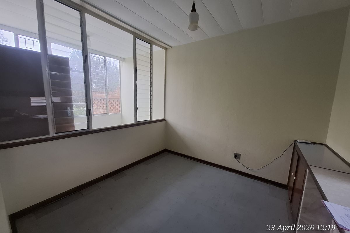 An empty bedroom featuring large windows, built-in cabinetry, and a simple ceiling light fixture, offering a blank canvas for renovation.